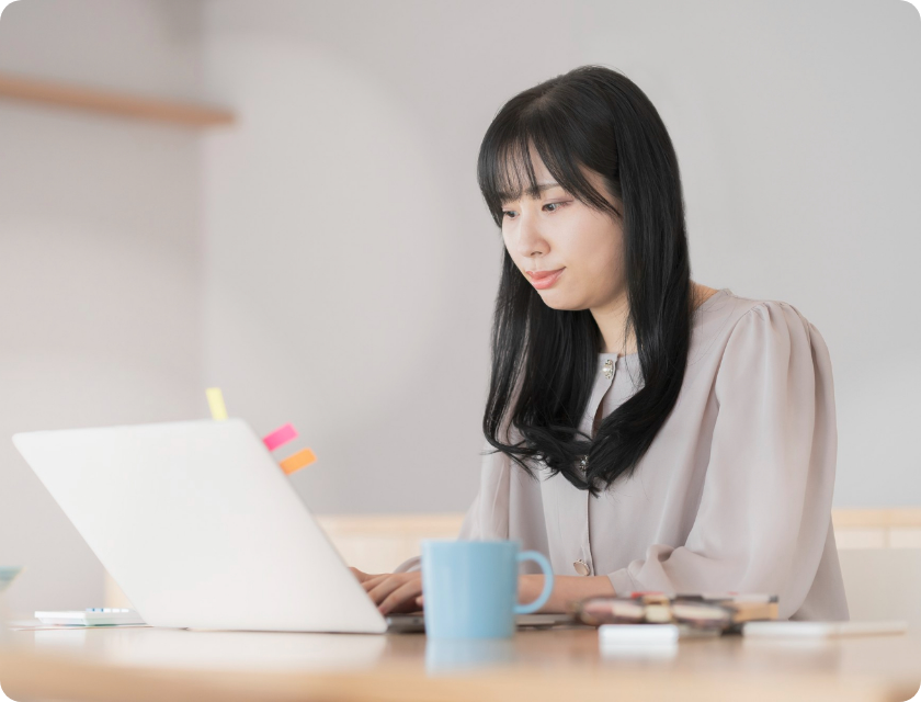 A girl siting in front of laptop with a cup